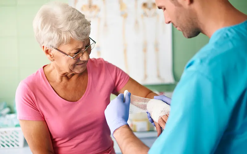 nurse wrapping womans wound with gauze